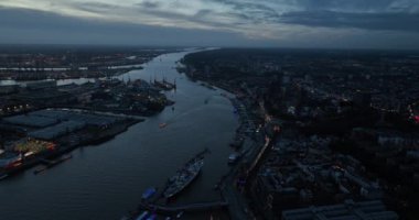 Gece karanlığında Hamburg, Elbe nehri ve şehir silueti üzerindeki hava aracı görüntüsü. Kuzey Almanya 'da büyük bir şehir.