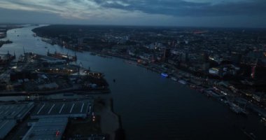 Alacakaranlıkta Hamburg 'un silueti, Elbe Nehri ve büyük ticari sanayi limanı. Şehir manzaralı. Hava aracı görünümü