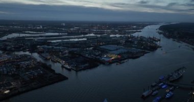Alacakaranlıkta Hamburg limanında hava aracı görüntüsü. Büyük sanayi tesisleri ve konteynır terminalleri.