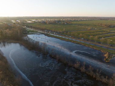 Hollanda 'daki kanallarda buz pateni. Kış gün batımı ve buzdaki insanlar. Hava aracı kuş bakışı.