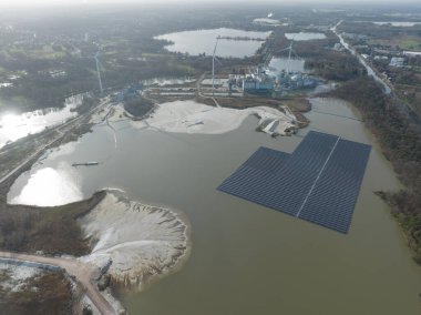 Aerial drone view on a floating solar panel park next to a large industrial factory complex and sand extraction site clipart