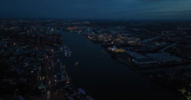 Hamburg 'daki Elbe Nehri ve geceleri nehir boyunca uzanan şehir merkezi. Bir tarafta Hamburg limanını, diğer tarafta da St Pauli şehir merkezini görüyoruz. Hava aracı görünümü.