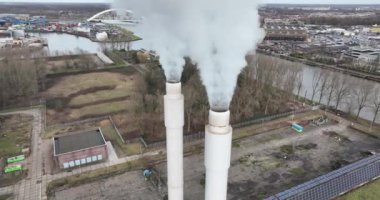 Hava aracı, endüstriyel bölgede sigara içilen iki bacaya bakıyor. Elektrik santralinin bir parçası. İklim değişikliği, ağır sanayi ve kirlilik.