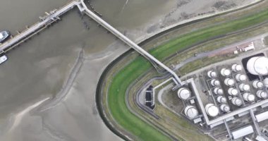 Rıhtımdaki petrol ürünleri depolama terminaline demirlenmiş bir geminin havadan aşağı görüntüsü. Terneuzen, Hollanda.