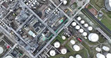 Kuşlar kimya endüstrisine tepeden bakan drone görüntüsü, depolama konteynırları, duman, borular, hatlar, tanklar, reyetoirler, duman yığınları, ağır sanayi faaliyette. Tesis ve kurulum.