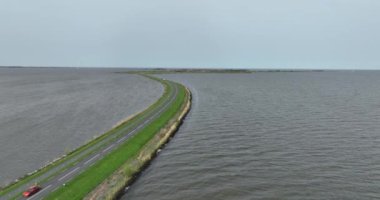 Doğa ve suyla çevrili sürücü yolunda havadan aşağıya insansız hava aracı videosu. Su boyunca yol. Araba nakli ve macera. Marken Yolu, Hollanda 'ya. Yol boyunca takip ediyorum..