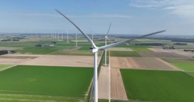 Sürdürülebilir enerji, güneşli bir gökyüzünün altındaki tarımsal alanlarda tek bir rüzgar türbini görüntüsü. Hava görünümü.