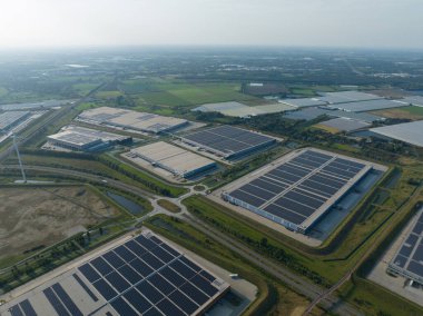 Hollanda, Venlo 'daki modern dağıtım merkezinin insansız hava aracı resmi. Çatıdaki güneş panelleri, büyük depolar..