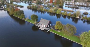 Loosdrechtse Plassen 'deki küçük evin hava aracı videosu. Hollanda 'da suyla çevrili küçük bir ev. Sonbahar renkleri.