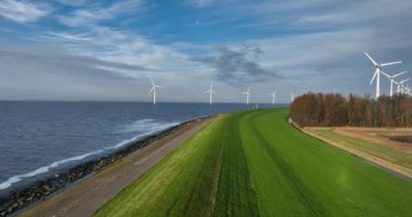 Su bariyerinin üzerinden uçmak, Dijk, su hattı boyunca, rüzgar türbinleri, temiz enerji, Hollanda, sel koruması. Tipik Hollandalı sahnesi. Hava görünümü.