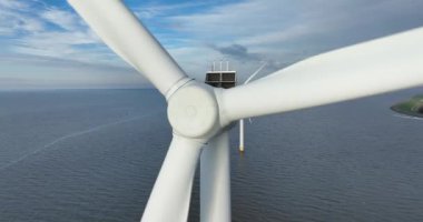 Kıyı rüzgâr parkının açıklarındaki rüzgâr türbiniyle ilgili bir hava aracı videosu. Enerji sistemini sürdürün. Rüzgar gücü.