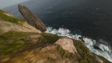 Azores, Sao Miguel, Portekiz 'deki engebeli kayalıklara dalış yapan Cliff. FPV hava görüntüsü.