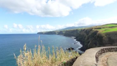 Adanın kayalıkları olan sahil şeridi Sao Miguel, Azores. Kayalar ve vahşi okyanus, yeşil çayırlar güneşli hava. Döndürme görünümü.