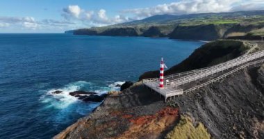 Azores 'in engebeli yamaçlarındaki küçük deniz feneri Sao Miguel, şamandıra, volkanik kayalar, bir hava aracı videosu.