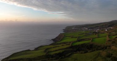 Portekiz, Azores 'deki kayalıklarla ve tarım arazileriyle dolu engebeli bir arazi. Günbatımı, Atlantik okyanus manzarası. Hava aracı görüntüleri