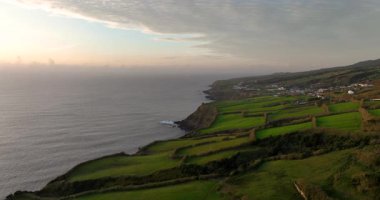 Portekiz, Azores 'deki kayalıklarla ve tarım arazileriyle dolu engebeli bir arazi. Günbatımı, Atlantik okyanus manzarası. Hava aracı görüntüleri