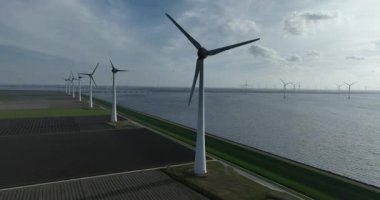 Su boyunca rüzgar türbinleri enerji geçişini sembolize ediyor. Fosil enerjiden yenilenebilir kaynaklara. Hava görünümü.