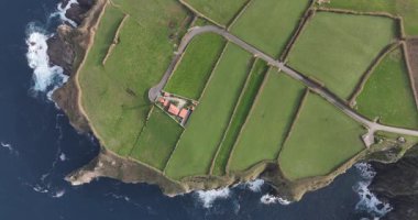 Portekiz, Azores, Sao Miguel adası, Atlantik Okyanusu 'ndaki kayalıklar kıyısındaki deniz fenerinin aşağı manzarası. Yukarıdan aşağıya insansız hava aracı görünümü.