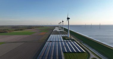 Hollanda 'daki zayıf enerji, rüzgar türbinleri, güneş panelleri. Su hattı boyunca. Doğa, rüzgar, güneş, bir hava aracı videosu