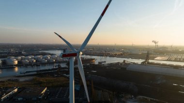 Amsterdam limanındaki rüzgar türbinlerinin yakın görüntüsü, ulaşım, kuru gövde, ticari ve endüstriyel taşımacılık. Gün batımı, altın saat. Hava görünümü.