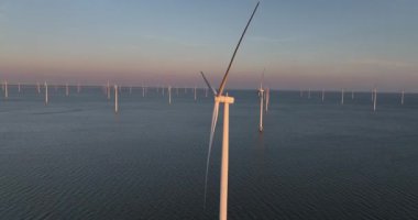 Rüzgar parkında rüzgar türbini, Afsluitdijk 'te yenilenebilir enerji Netehrlands, off-shore rüzgâr çiftliği, günbatımı, hava aracı videosu