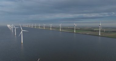 Suyun üzerindeki rüzgar türbinleri, su hattı boyunca, temiz enerji, polder arazisi, yenilenebilir rüzgar enerjisi, enerji üretimi. Hava aracı videosu. Hollanda 'da..
