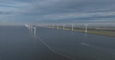 Suyun üzerindeki rüzgar türbinleri, su hattı boyunca, temiz enerji, polder arazisi, yenilenebilir rüzgar enerjisi, enerji üretimi. Hava aracı videosu. Hollanda 'da..