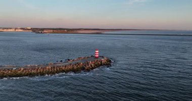 Kuzey Denizi 'ne doğru ilerleyen bir iskele. Küçük deniz feneri feneri, Ijmuiden, Hollanda. Günbatımı hava görüntüsü.
