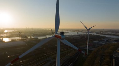 Amsterdam limanında rüzgar türbini, ağır sanayi, su üzerinde ulaşım ve yenilenebilir enerji sergiliyor. Gün batımında hava aracı fotoğrafı.
