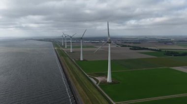 Yenilenme enerjisi, 60 FPS, temiz enerji, rüzgar türbinleri, deniz kenarındaki rüzgar parkı. Hava aracı görünümü.