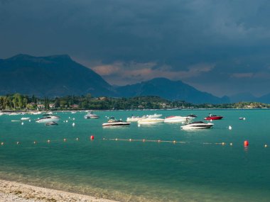 Yaz akşamında Garda Gölü, yağmurdan önce, güney batı manzarası. Rıhtımlar arasında demirlemiş yatlar ve motorlu tekneler. İtalya 'daki en büyük göl. 