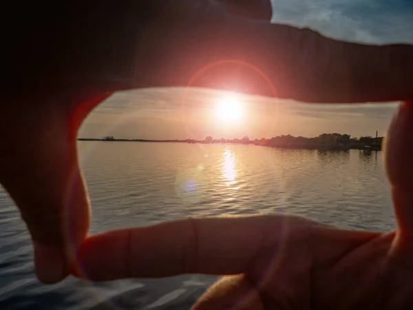 在夕阳西下的海面上 用手指形成的一种姿势 在平静的海面上从低太阳发出的耀斑 — 图库照片