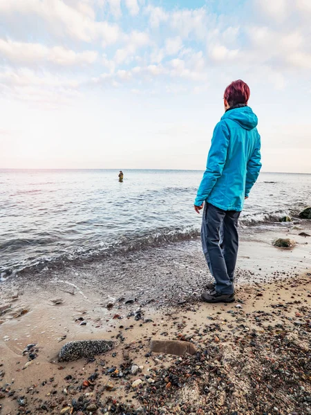 女人正在看着渔夫在冷水中涉水 人在水里呆得很深 用钓竿拉鱼饵 德国波罗的海海岸 — 图库照片