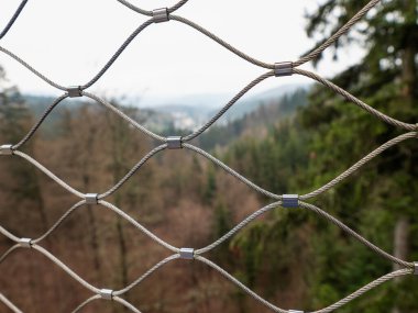 Modern krom çelik tel örgüler, yeşil ağaç tepelerinde baskılı eklemleri olan