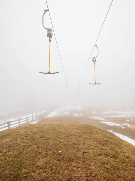 Empty t-bar lift in heavy fog in Ore mountains, Klinovec. End of season in foggy weather