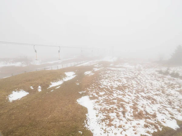 Empty t-bar lift in heavy fog in Ore mountains, Klinovec. End of season in foggy weather