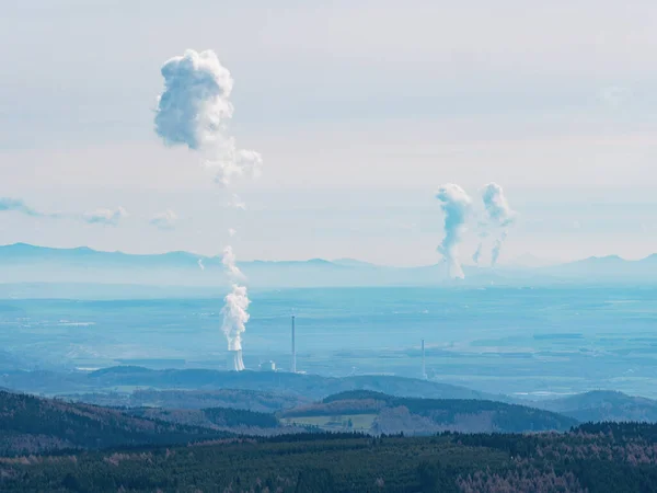 Smoking coal-fired power plant and steam cloud above  cooling tower. Ecological burden and environmental problem. Ore Mountains, Czech Republic