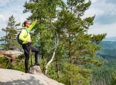 Kızıl saçlı sporcu gözleri gölgede bırakıyor. Erkek turistler sarı forma giyer. Kum taşı yürüyüş parkurunda. Sırt çantalı ve güneş gözlüklü bir adam, yürüyüş sopası kullanıyor.. 