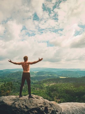Kollarını kaldırmış, mutlu, üstsüz bir adam. Dağdaki keskin kayalıklardan gelen vahşi manzara çığlıkları. Sıra dışı spor