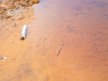 Zehirli maden suyu. Büyük kayaların üzerindeki tortulu kırmızı feribot çamuru, Polonya 'nın Alman sınırındaki eski İngiliz taş ocağı Babina..