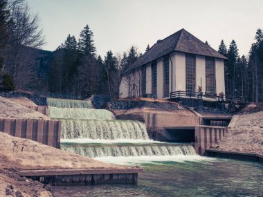 Bir gece fırtınasından sonra hızlı suda elektrik santrali dağlardan mavi göle akar Walchensee, Dolomites Alpleri