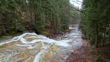 Harrachov, Çek Cumhuriyeti - 04 19 2025: Krkonose dağlarında yağmurlu bir bahar günü Mumlava Şelalesi 'nde gezen ve fotoğraf çeken turistler