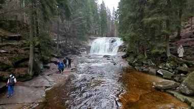 Harrachov, Çek Cumhuriyeti - 04 19 2025: Krkonose dağlarında yağmurlu bir bahar günü Mumlava Şelalesi 'nde gezen ve fotoğraf çeken turistler