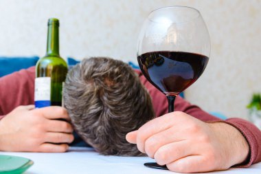 Kontrolsüz alkol tüketimi, alkolizm hastalığı, şarap şişesi ve bardakların kapatılması. Kontrolsüz alkol tüketimi kavramı. Evde sarhoş bir adam var..