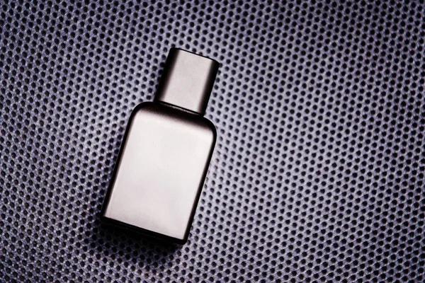 stock image Men's fragrance of perfume or eau de toilette.Advertisemental photo of a black bottle on a dark background. Layout for copy space.