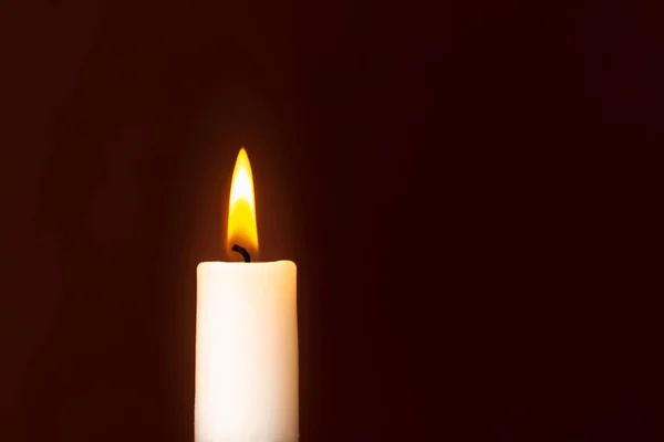 Candle flame on a dark background, symbol of prayer and remembrance.Religion concept.Closeup.Copy space.