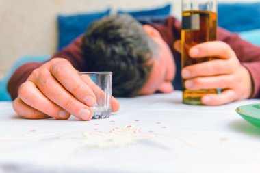 Kontrolsüz alkol tüketimi, alkolizm hastalığı, bir şişe alkol ve cam kapanışı. Kontrolsüz alkol tüketimi kavramı. Yurtiçinde sarhoş bir adam..