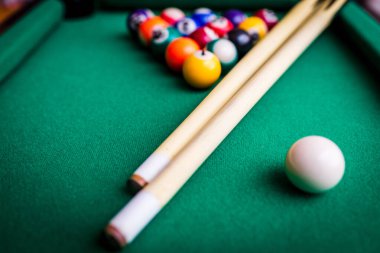 Bilardo sporu kavramı. Bilardo oynamak. Bilardo ıstakaları ve yeşil bilardo masasında çok renkli bilardo topu piramidi..