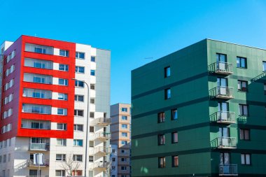 Satılık daireleri olan yeni yapılmış parlak renkli bir bina. Kırmızı turuncu ve yeşil apartman blokları. Yeni yenilenmiş konut alanında yeni bitirilmiş modern tarz apartman..
