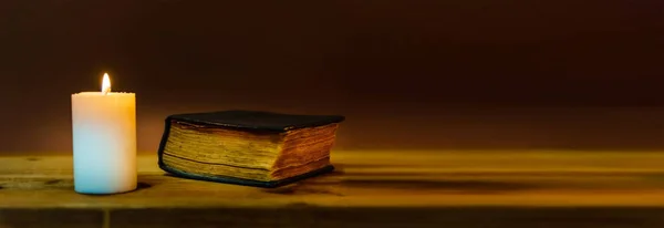Banner image.Candle with bible on a old wooden table.Beautiful Religious background.Religion concept.